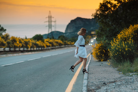 A woman in a white dress is running down a roadの写真素材