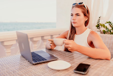 Woman coffee cafe. Woman sitting at a coffee shop with mobile phone drinking coffee and looking away. Caucasian female relaxing at a cafe.の写真素材