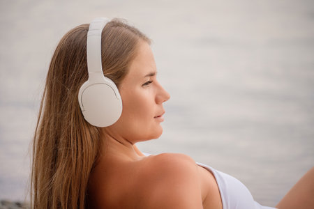 A woman wearing headphones is laying on the beachの写真素材