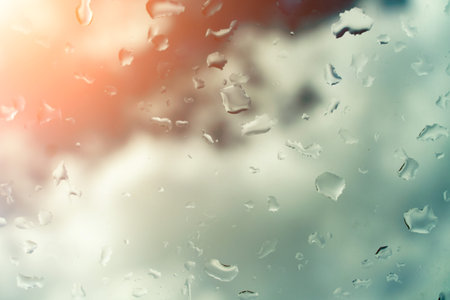 Water drops on glass against blue sky, rainy season concept. Window view background screensaver