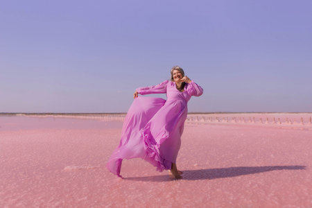 Pink Lake Woman Dress Photo Shoot - A woman wearing a pink dress poses on a pink salt lake.の写真素材