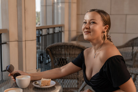 Woman, Coffee, Cafe: Smiling Woman Enjoying Coffee and Cake on a Cafe Patio.の写真素材