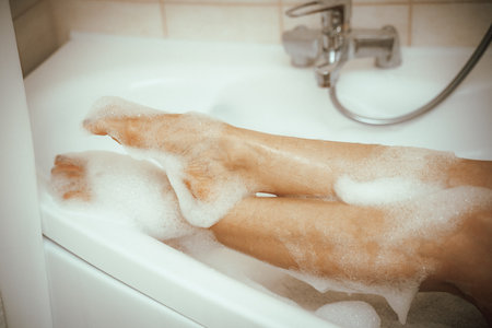 Womens feet in bath foam. View from above. Enjoy and relax in a spa hotel