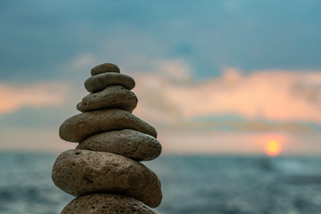 Rocks Stack Sunset Beach - A balanced stack of rocks stands against a beautiful sunset over a calm...