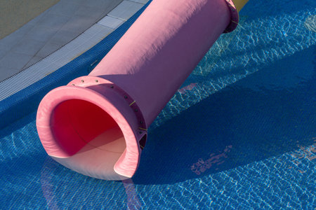 Water Slide Pool Summer Fun - Pink water slide ending in a pool of blue water on a sunny day, ready...
