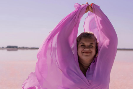 Woman Pink Lake Scarf Joy - A woman smiles while holding a pink scarf in the wind on a pink lake.の写真素材