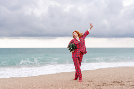 Sea Lady in plaid shirt with a christmas tree in her hands enjoys beach. Coastal area.の写真素材