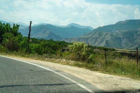 A road with a fence on the side and a mountain in the backgroundの写真素材