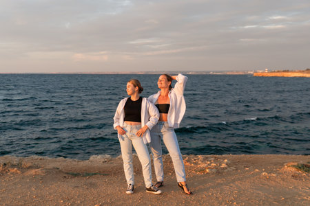 Friends Beach Sunset Pose - Two women pose by the ocean at sunset.の写真素材