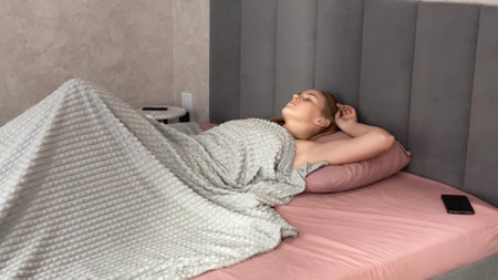 Woman Bedroom Wakeup Morning: Relaxed woman waking up in bed, enjoying morning, bedroom setting.の写真素材