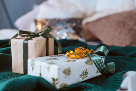 Two presents are sitting on a green blanket. One of them is wrapped in a tree patterned wrapping...