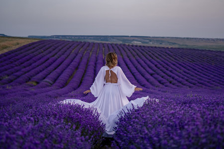 A woman is standing in a field of purple flowersの写真素材