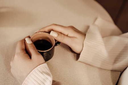Coffee Hands Cozy: Woman enjoys espresso indoors, relaxing, warmth.の写真素材