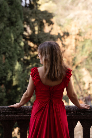 Woman Red Dress Autumn Balcony: Contemplative view from a balcony overlooking autumnal scenery.の写真素材