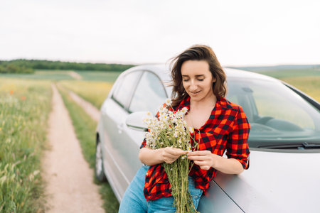 A woman is sitting on the side of a road with a bouquet of flowers in her handの写真素材