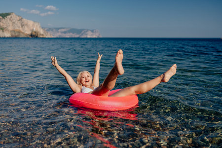 A woman is in the water with a red inflatable tubeの写真素材