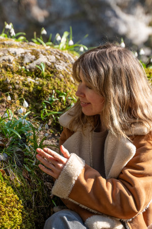 Woman Nature Spring Flowers: Peaceful contemplation near waterfall, showcasing serenity amidst blooming wildflowers in springtime.の写真素材