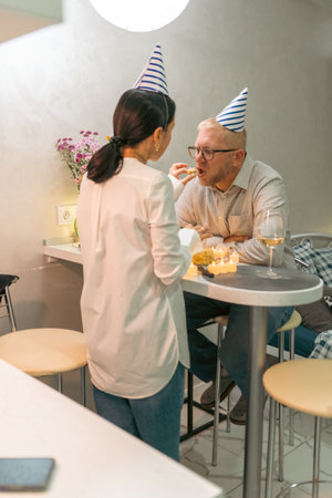 Birthday Couple Cafe Celebration: Elderly man woman celebrating birthday indoors cafe, enjoying snacks and drinks.の写真素材