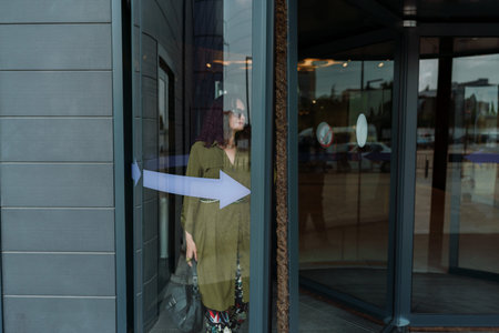 Woman leaves a supermarket. Caucasian model with long brunette hair, wears sunglasses.
