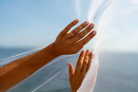 A woman stands on a beach with a white veil over her head. The scene is serene and peaceful, with the womans gaze directed towards the water.の写真素材