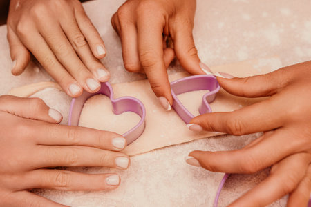 Hands Cookie Cutters Baking - Close-up of hands using cookie cutters to cut out heart shapes from dough.の写真素材