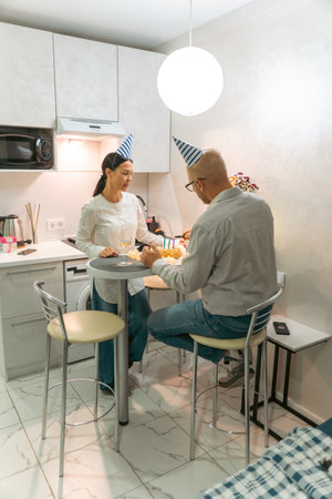 Couple Kitchen Birthday Party: Celebrating birthday, playing game indoors; joyful intimate moment.の写真素材
