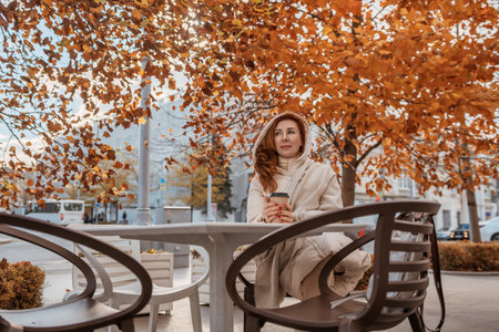 Woman Coffee Autumn Park: Relaxing outdoors, enjoying fall foliage, warm beverage.の写真素材