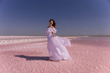 Woman White Dress Pink Salt Lake - A woman in a white dress stands on a pink salt lake, enjoying the sunny day.の写真素材
