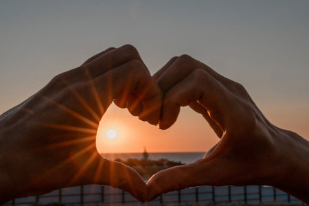 Sunset Heart Hands Beach - Silhouette of hands framing a sunset over the beach, forming a heart shape.の写真素材