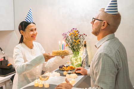 Birthday Cake Celebration Couple: Woman presents birthday cake to man at home during intimate...