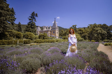 A woman stands in a field of lavender flowers, wearing a white dressの写真素材