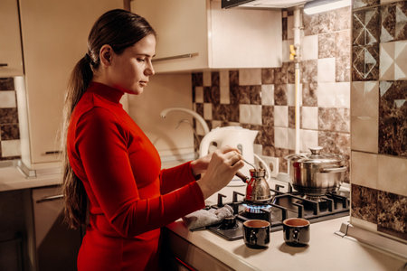 Woman Kitchen Coffee Preparation: Evening domestic scene showing woman making coffee in her kitchen.の写真素材