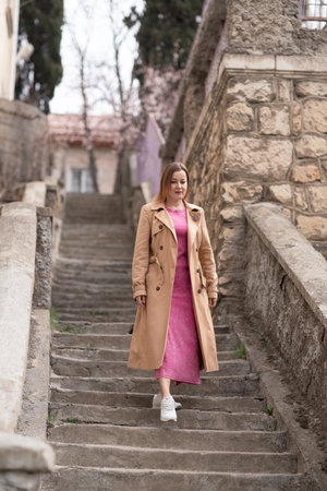 Trenchcoat Woman Stairs Walking, daytime, for exercise up stone steps outside.の写真素材