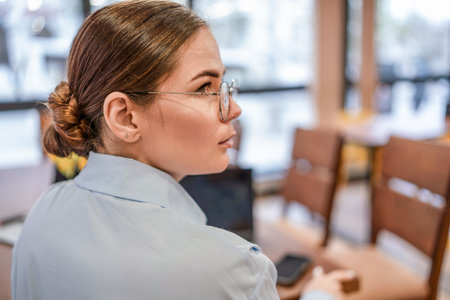 Woman Glasses Office: Focused woman works in office setting during daytime for professional tasks.の写真素材