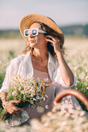 Daisies Woman Summer: Woman rests in daisy field during summer, holding flowers, seeking relaxation.の写真素材