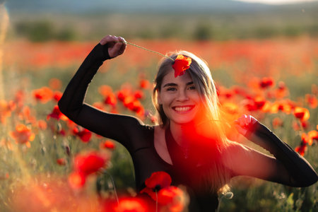 Poppy field girl: Woman smiles with poppy flower during daytime in a poppy field, happy.の写真素材