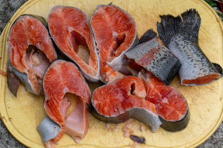 Salmon Steaks Food Prep: Fresh cut fish displayed for cooking on yellow cutting board in kitchen.