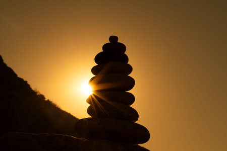 Cairn sunset balance stacked stones silhouette on rock at golden hour representing zen meditation