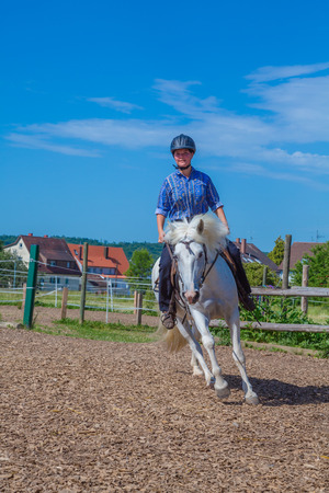 young woman is riding a white horseの写真素材