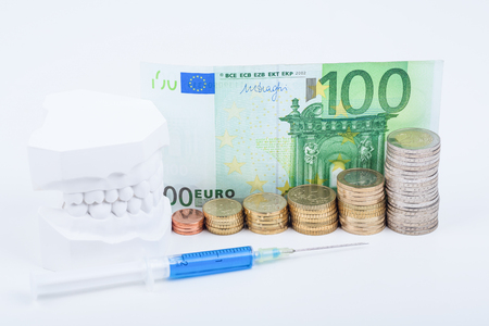 money, syringe and teeth on whiteの写真素材