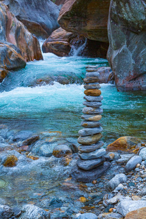 stone pyramid at the wild and cold mountain river in italyの写真素材