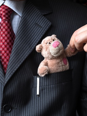 The elegant stylish businessman keeping cute teddy bear in a his breast suit pocket. Formal negotiations conceptの写真素材