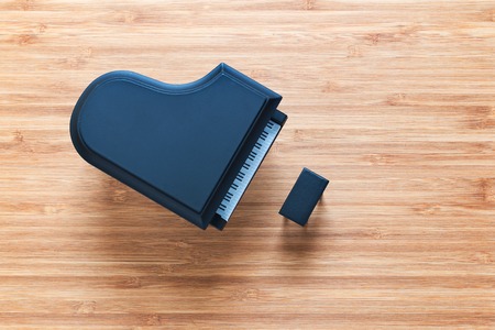 Black toy grand piano on a wooden floor with stool standing near it. Top view. Music conceptの写真素材
