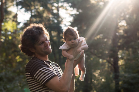 Happy joyful father having fun throws up in the air his child against the sunset background - intentional sun glare and vintage color, lens focus on father. Fathers day. Film filterの写真素材