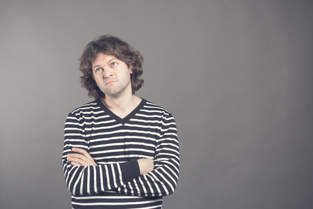 Portrait of caucasian man with bored fed up expression, looks displeased up, being tired to explain his wife where he was at night. Shaggy guy in stripes shirt tired and bored to listen to bullshit.の写真素材