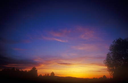 Beautiful multicolored sunset over a dark landscape の写真素材