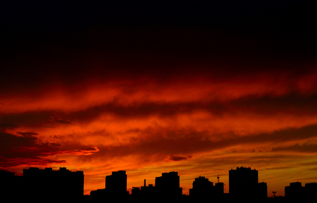 Dramatic red sunset over a dark cityscape.の写真素材