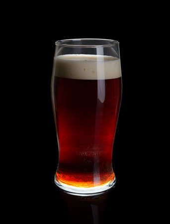A glass of dark beer isolated on black background.の写真素材