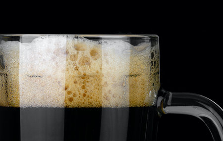 A mug of dark beer isolated on black background.