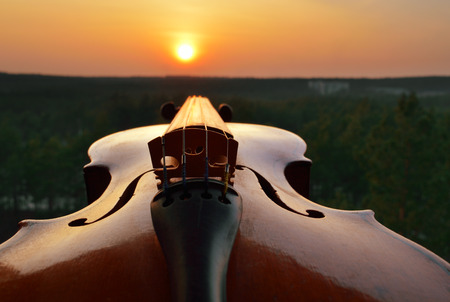 Old violin against a sunset sky.の写真素材